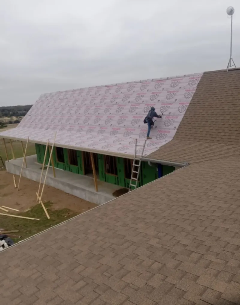 Worker preparing underlayment for a metal roof installation in Woodland Park